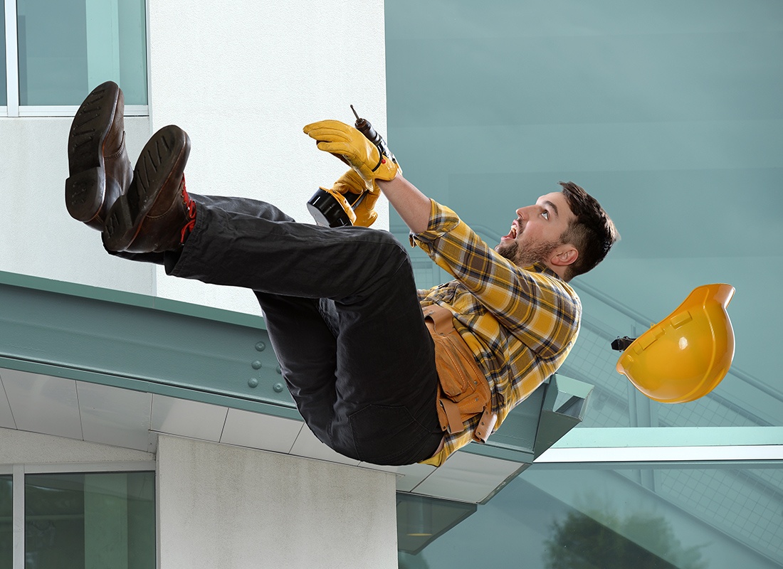 Business Insurance - Worker Falling Off a Building With a Drill in Hand and Hat Flying Off