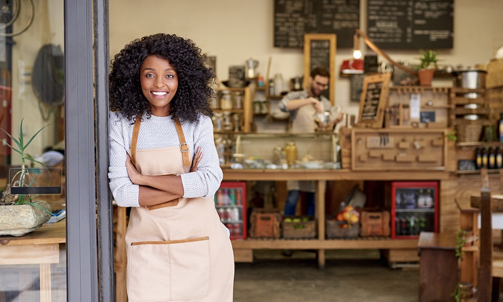 4 Pain Points for the Small Business Owner - Friendly Business Owner Standing in Front of Her Shop