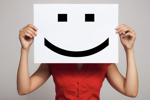 7 Tips to Keep Employees Motivated - Woman Holding a Happy Face Mask