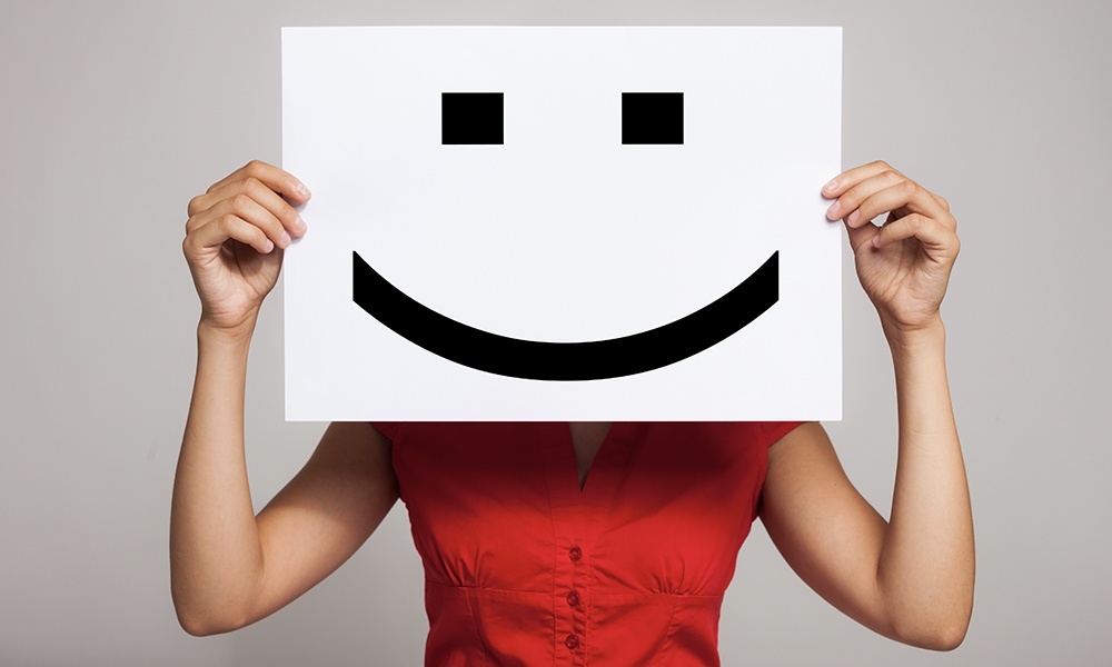 7 Tips to Keep Employees Motivated - Woman Holding a Happy Face Mask